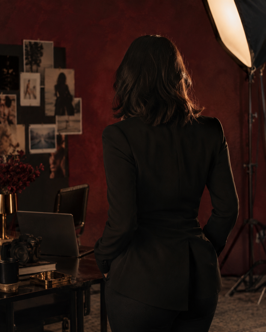 An adult creator, seen from behind, in a warm photography studio
